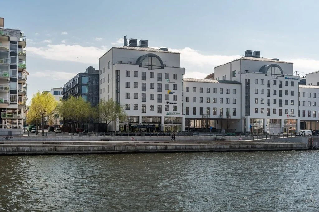 Kontorsbyggnad vid vattnet i Stockholm med Compliors skylt på fasaden.